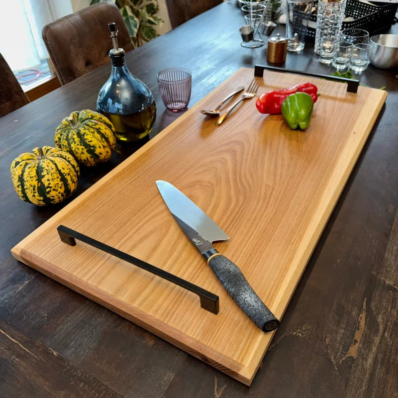 Massivholz Schneidebrett mit Metallgriffen auf dunklem Tisch für Grillgerichte und Vorspeisen